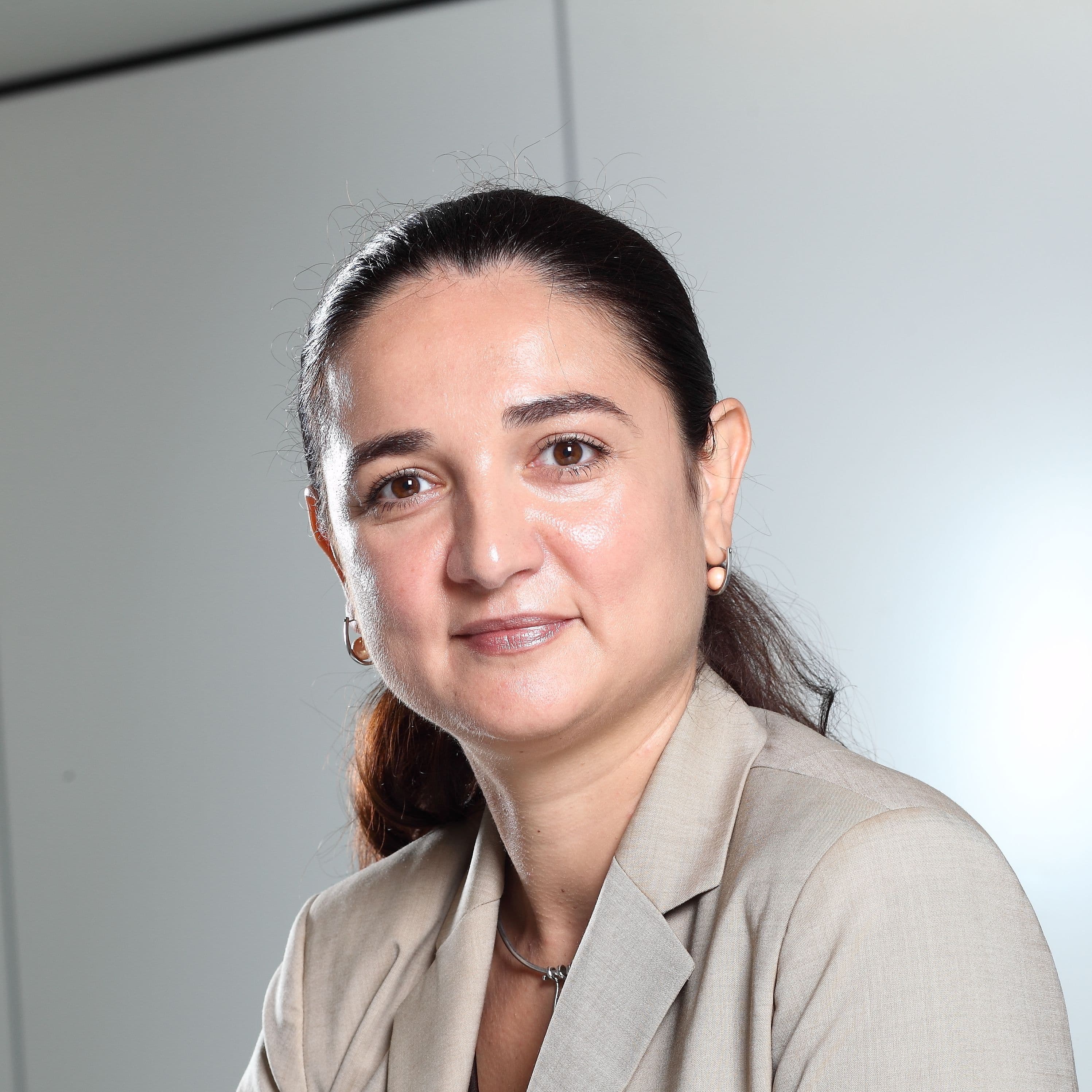 Professional woman with dark hair pulled back, wearing a light-colored blazer.